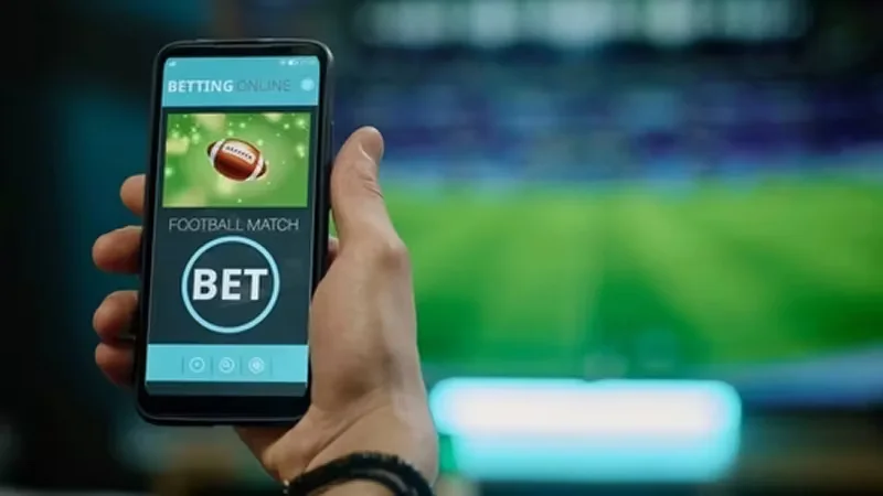 Focused Bangladeshi fan following live cricket data and numbers across several smart monitors.